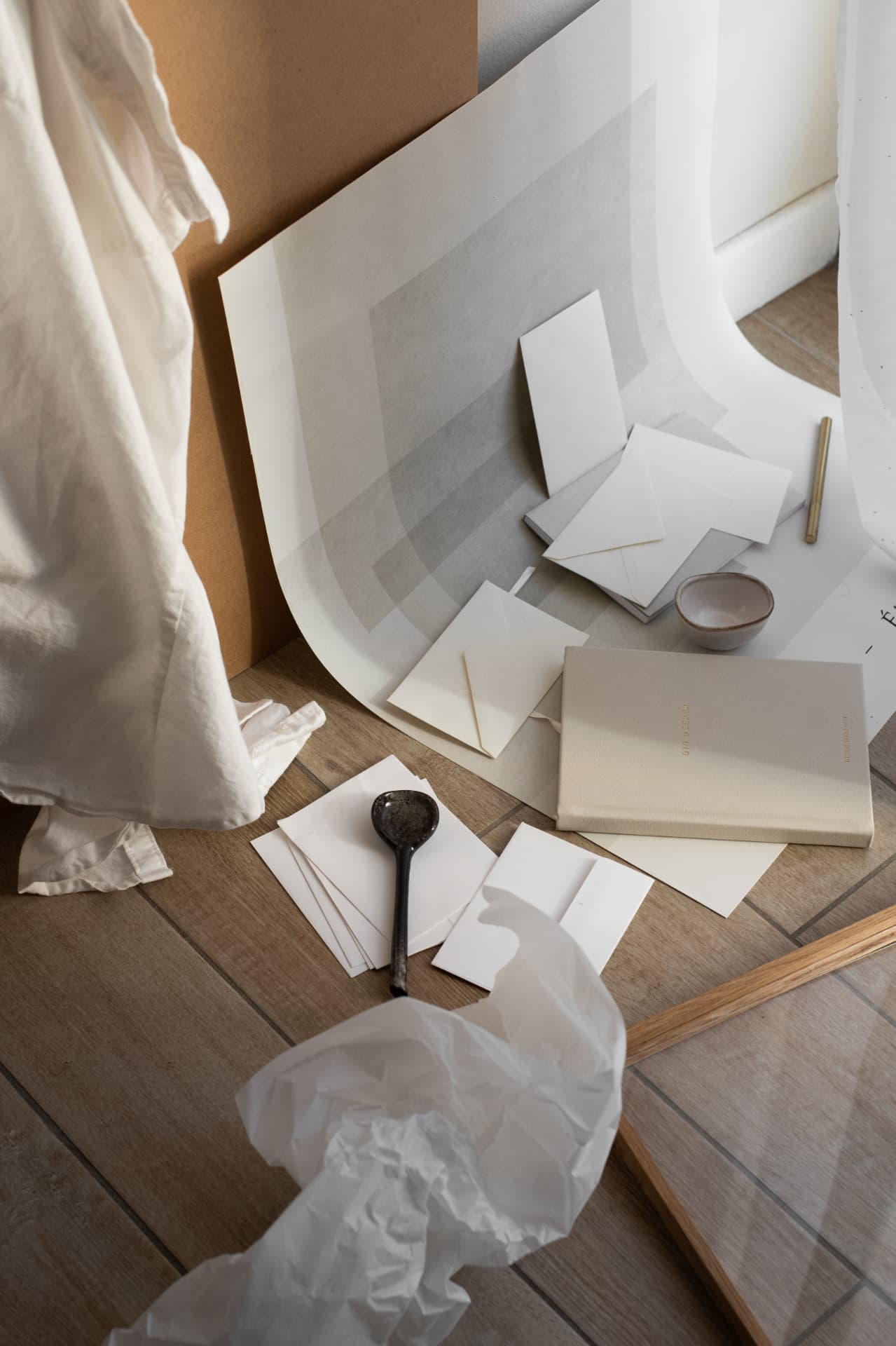 Cream paper, envelopes and a journal arranged on a studio floor