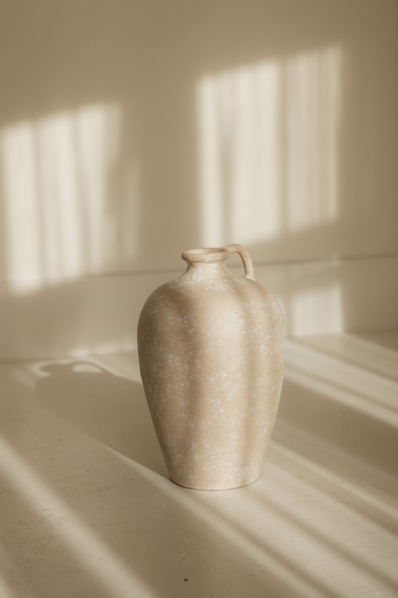 A pale ceramic vessel in soft window light