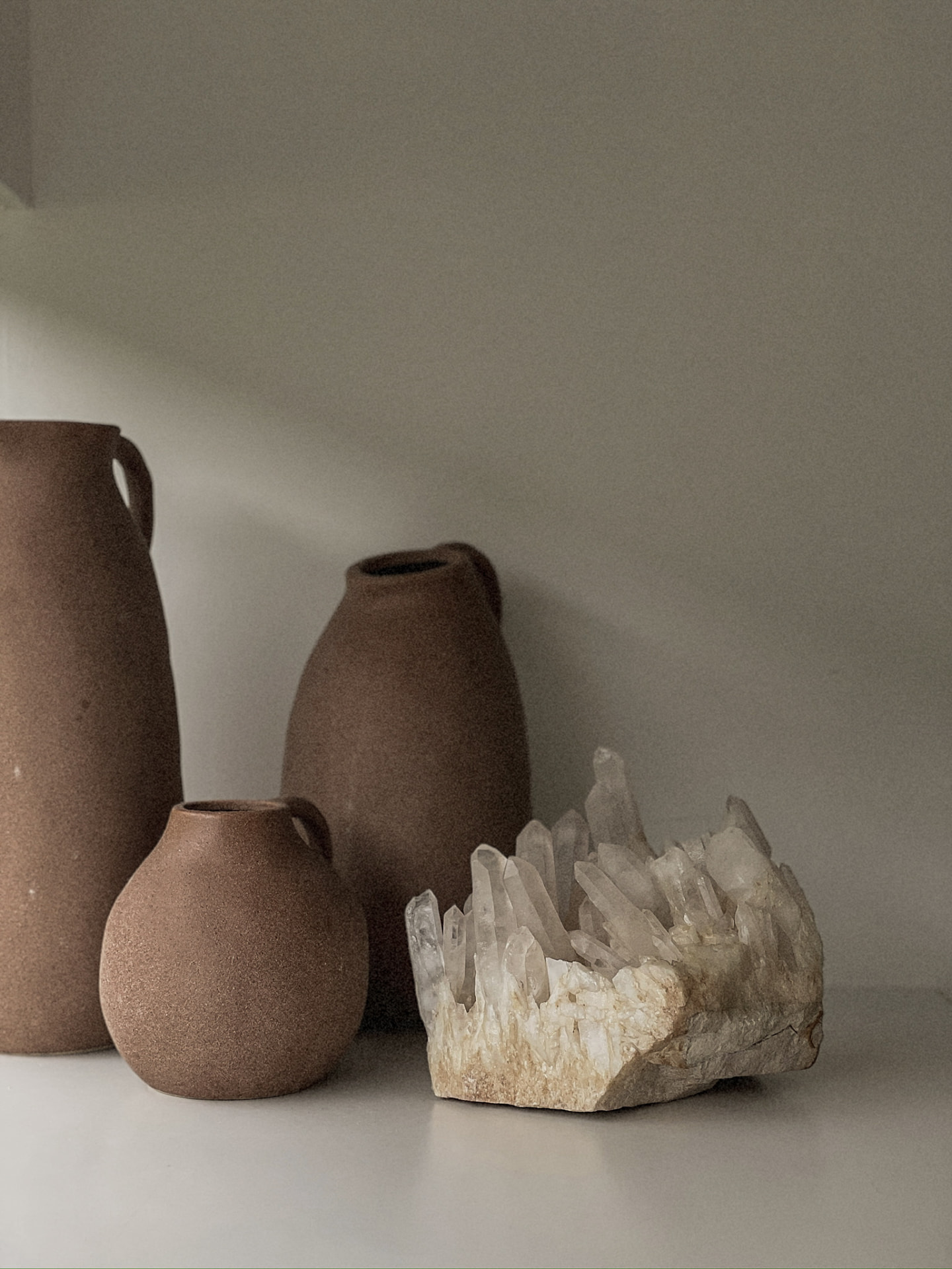 Terracotta vessels beside a raw quartz crystal cluster