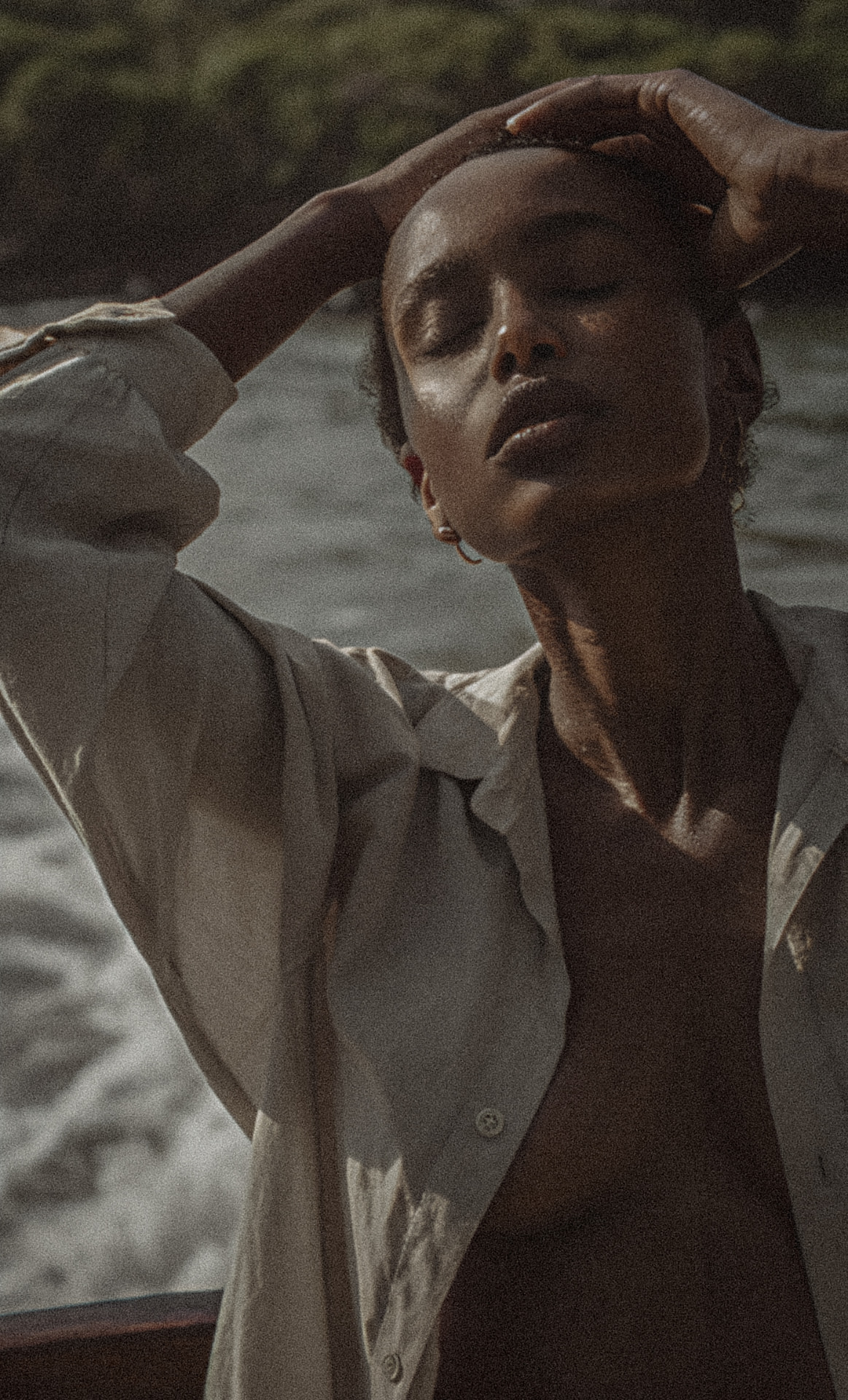 A woman wrapped in white linen holding seashells by the shore